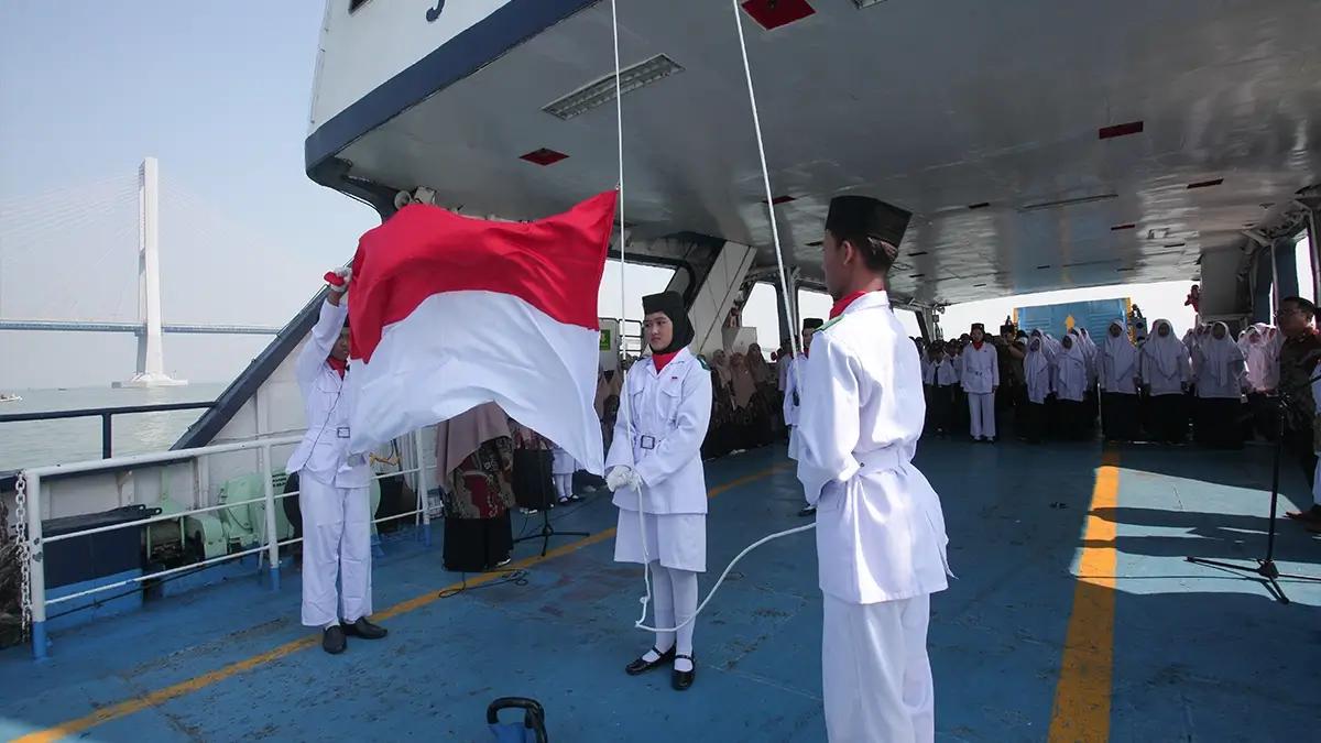 Paskibra mengibarkan bendera Merah Putih saat upacara bendera di atas kapal feri KMP Joko Tole di Selat Madura, Jawa Timur, Sabtu (17/8/2024). Upacara di atas kapal feri yang diikuti sekitar 250 pelajar SMP Muhammadiyah 2 Surabaya itu untuk memperingati HUT Ke-79 Kemerdekaan RI. ANTARA FOTO/Didik Suhartono/wpa.