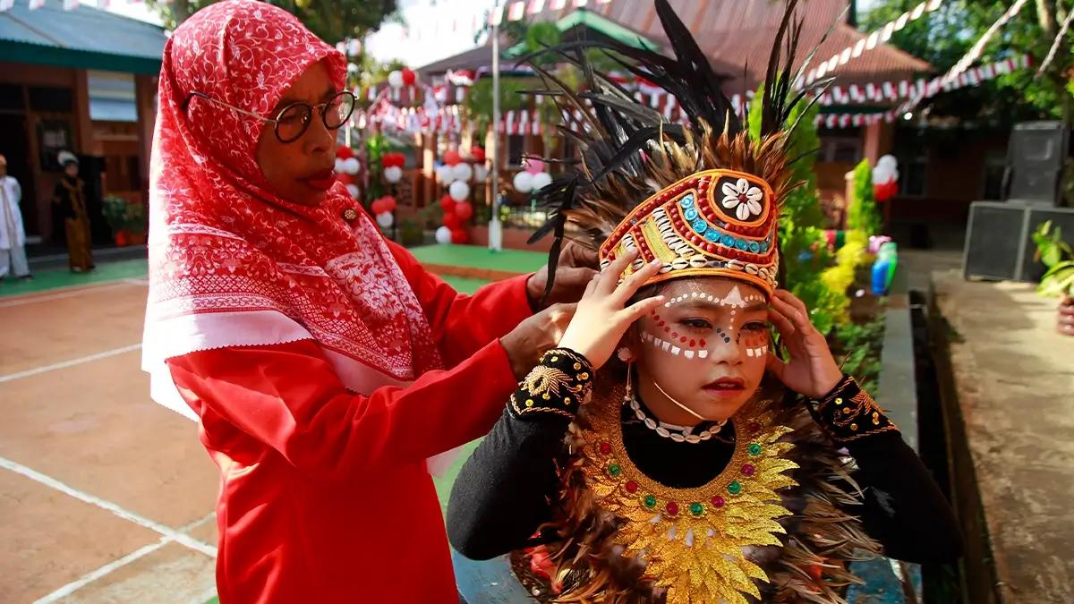 Seorang guru memperbaiki atribut peserta paduan suara sebelum mengikuti upacara bendera di SD Negeri 1 Kota Ternate Maluku Utara, Sabtu (17/8/2024). Upacara yang diikuti siswa dan guru SD Negeri 1 Kota Ternate tersebut untuk memperingati HUT Ke-79 Kemerdekaan RI tersebut guna menanamkan jiwa nasionalisme kepada peserta didik sejak dini. ANTARA FOTO/Andri Saputra/wpa.