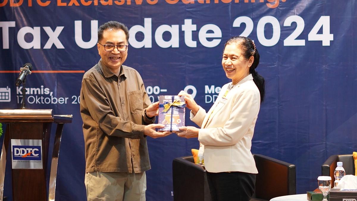 Founder DDTC Danny Septriadi membagikan buku secara simbolis kepada Herlina Trisnawati dari PT Aisin Indonesia sebagai peserta dalam DDTC Exclusive Gathering: Tax Update 2024 di Menara DDTC, Kamis (17/10/2024). 